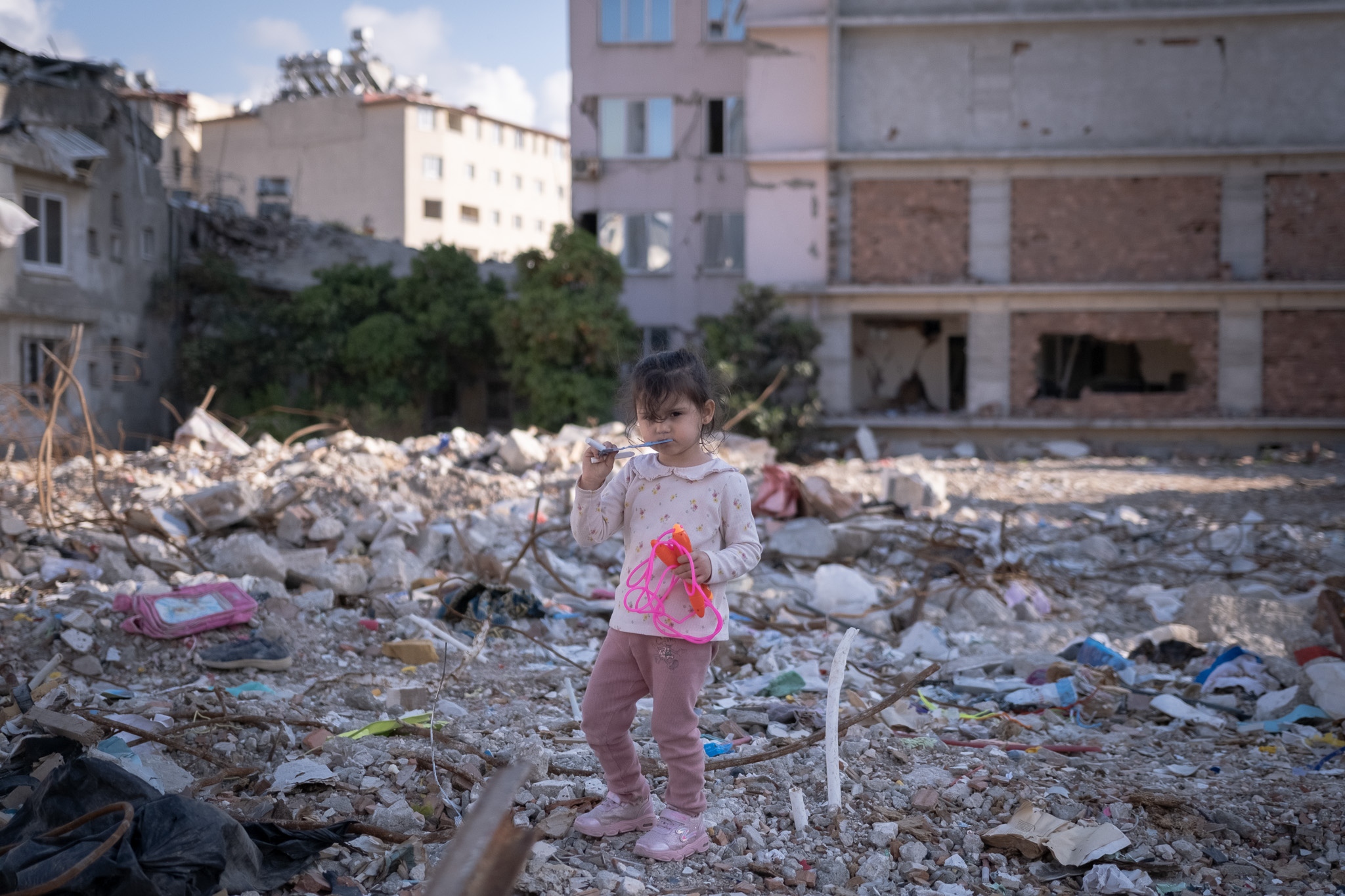 &nbsp;A girl walks around the rubble looking for toys...