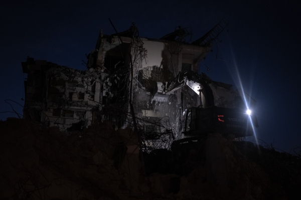 A demolition team tearing down a building during nighttime. 
